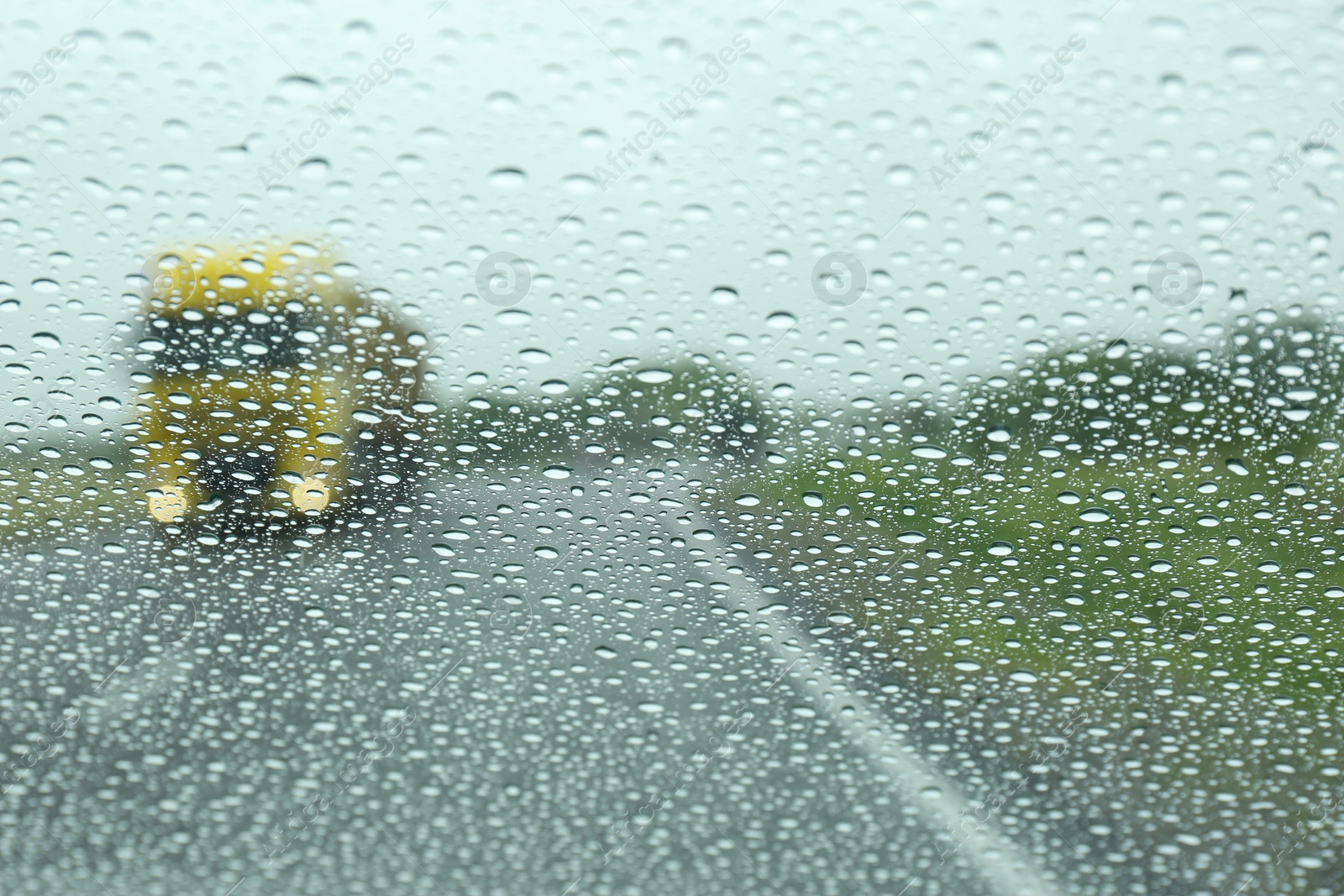 Photo of Blurred view of country road through wet car window. Rainy weather