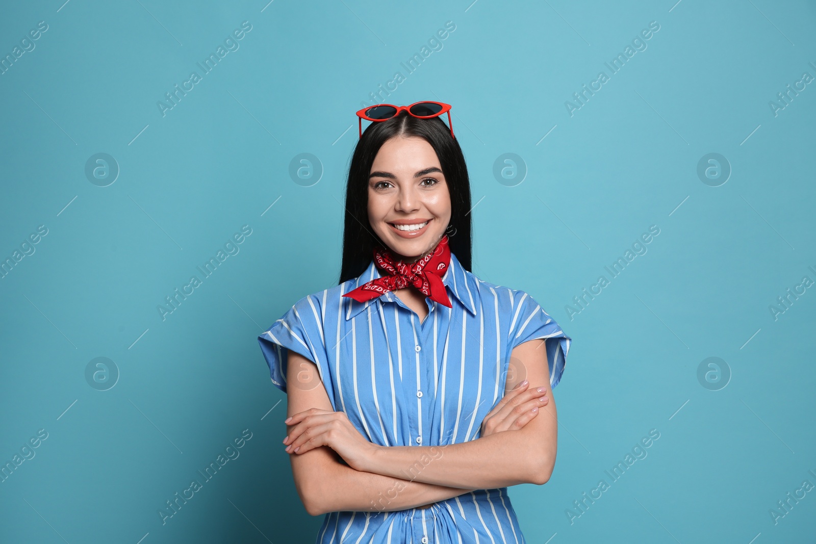 Photo of Fashionable young woman in stylish outfit with bandana on light blue background