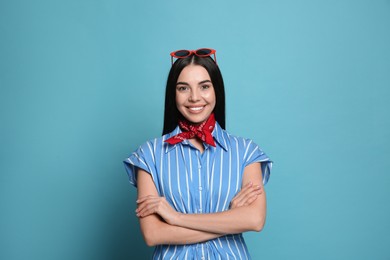 Fashionable young woman in stylish outfit with bandana on light blue background