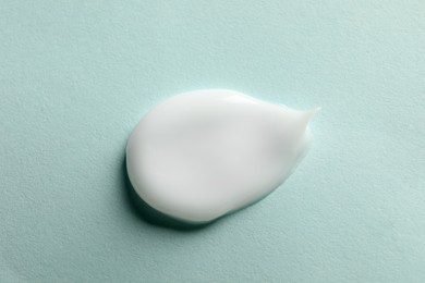 Photo of Sample of face cream on light blue background, top view