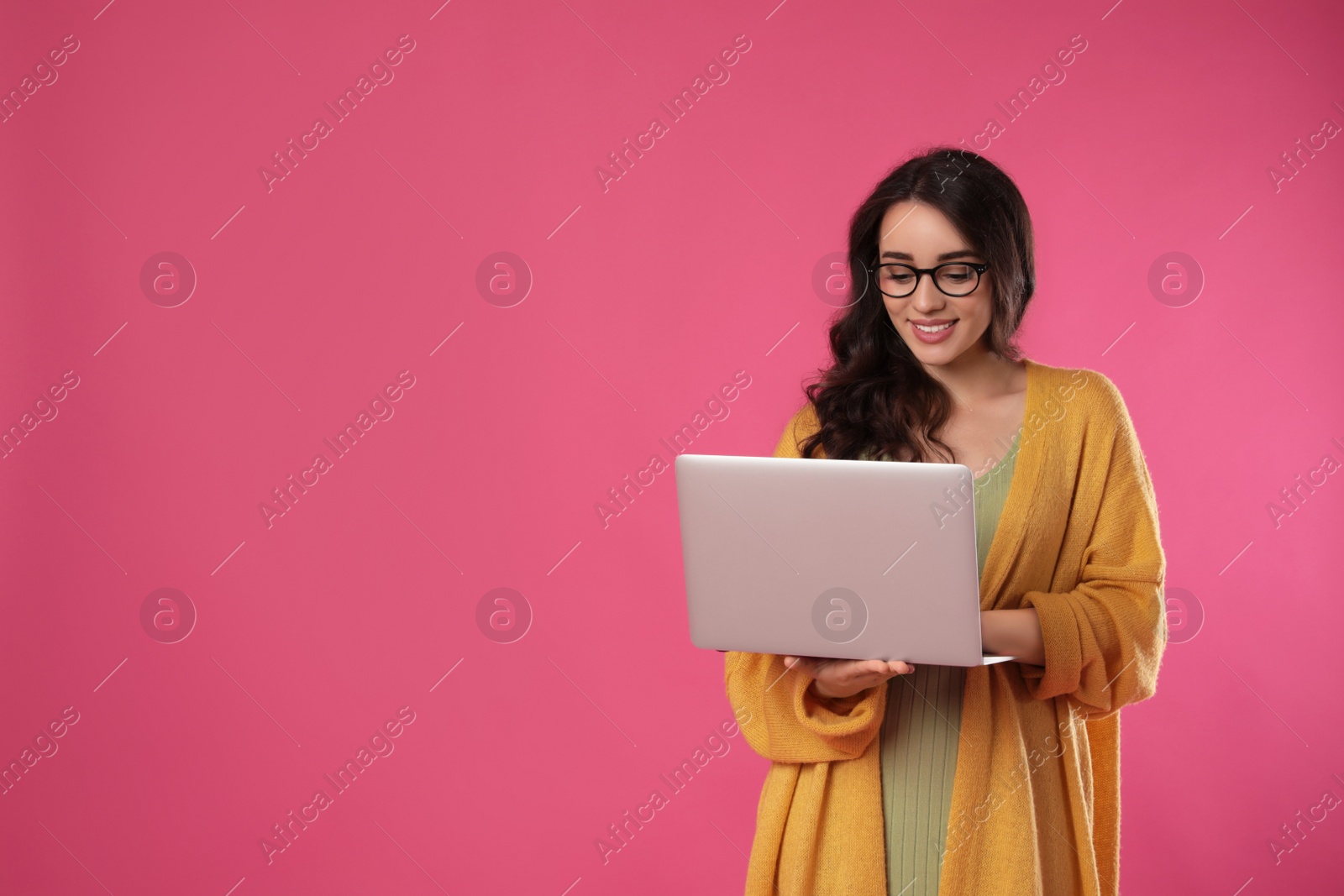 Photo of Young woman with laptop on pink background. Space for text