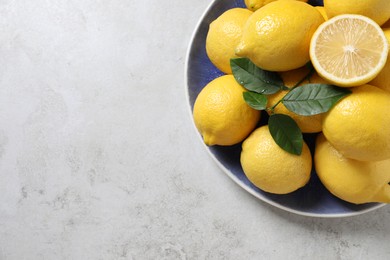 Fresh lemons and green leaves on table, top view. Space for text