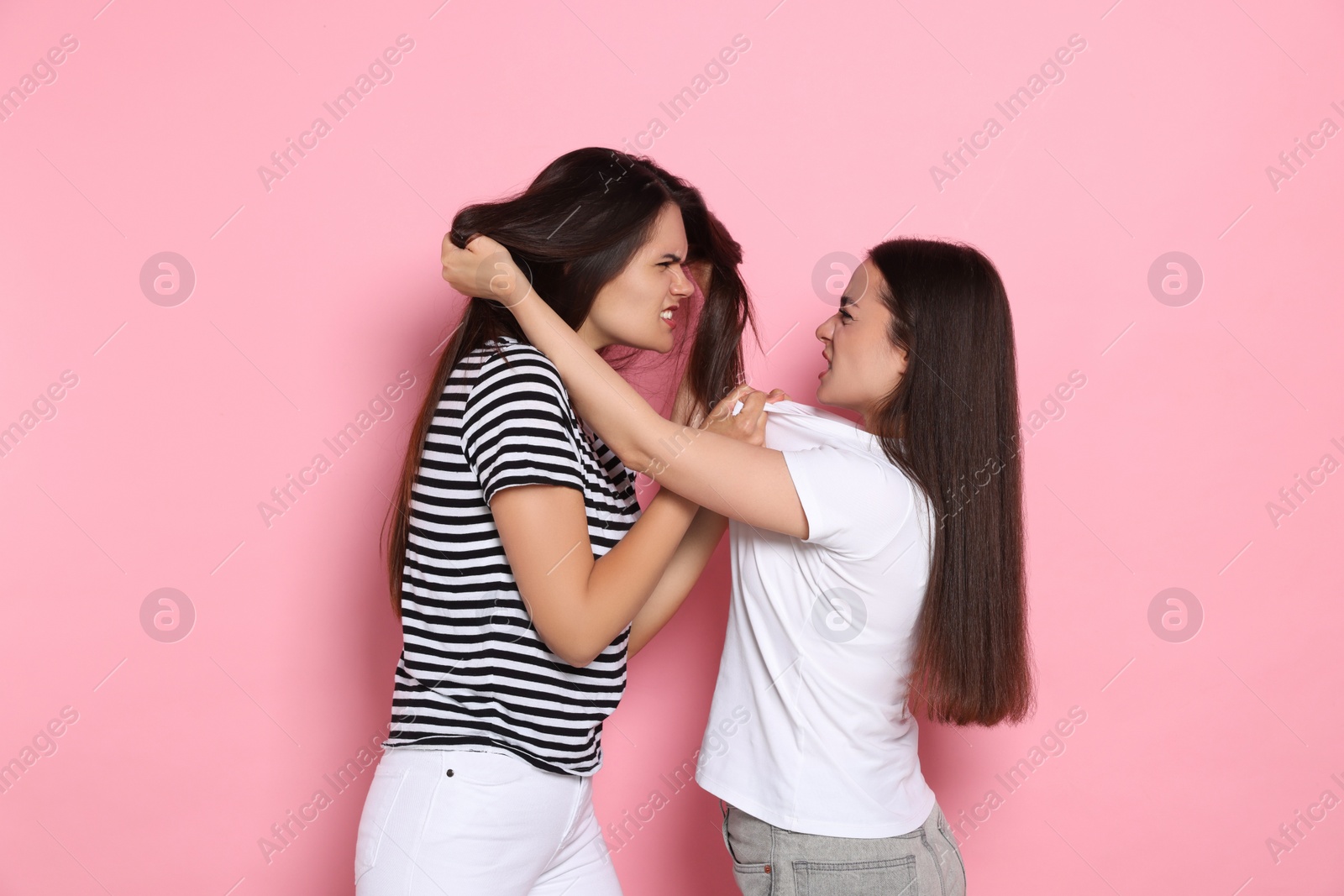 Photo of Aggressive young women fighting on pink background