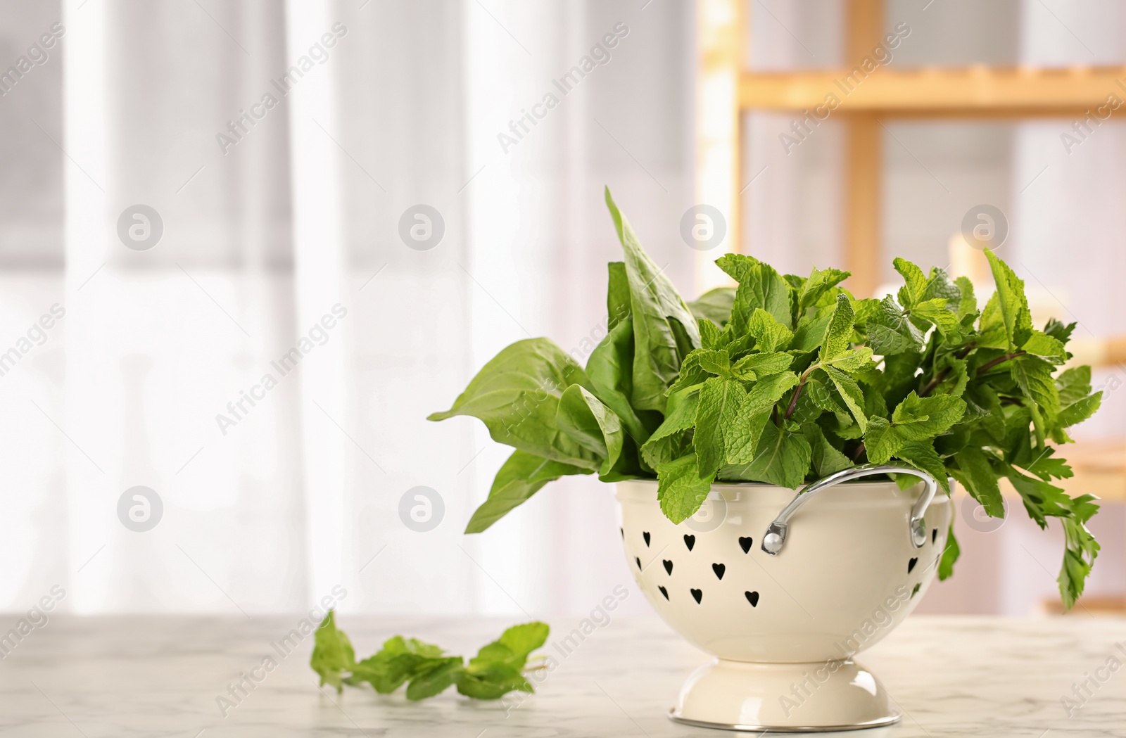 Photo of Colander with fresh herbs on table