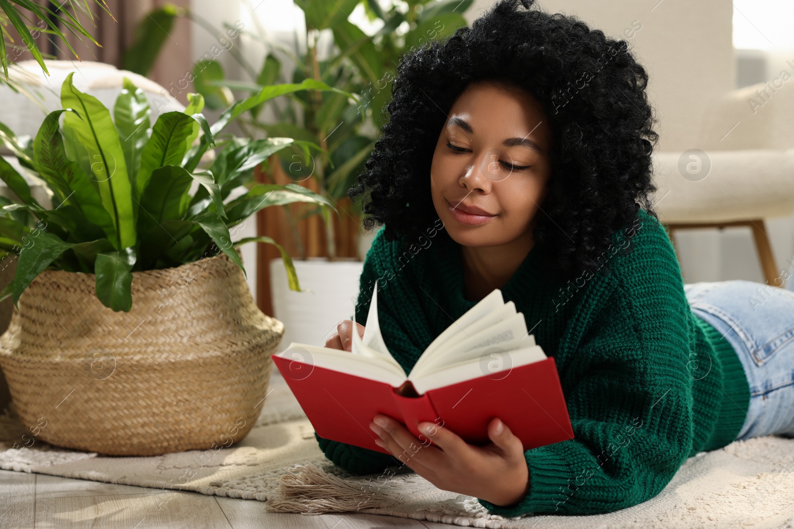 Photo of Relaxing atmosphere. Woman reading book near potted houseplants at home