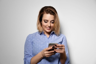 Photo of Portrait of beautiful young woman using smartphone on light background