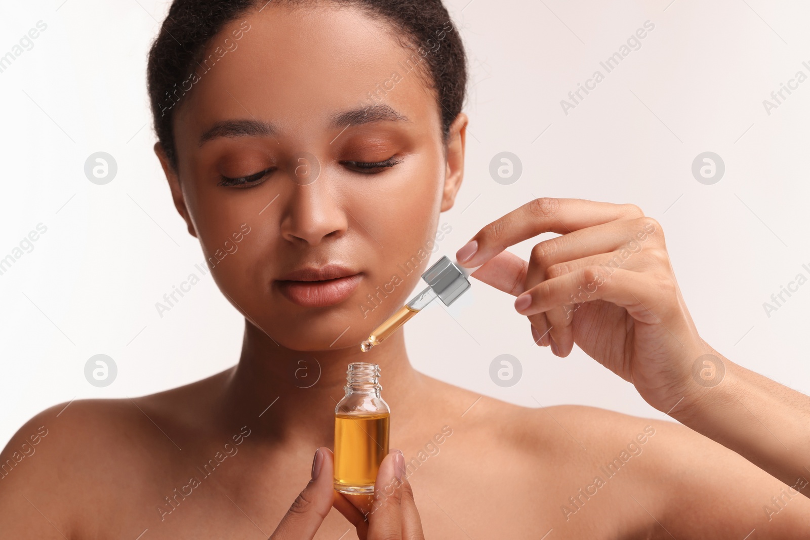 Photo of Beautiful woman with bottle of serum and dropper on white background