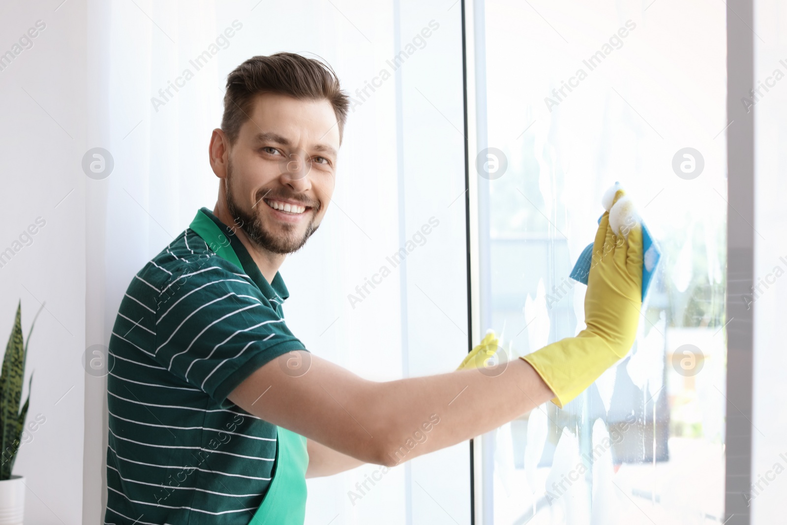 Photo of Male worker washing window glass at home