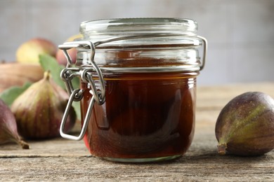 Photo of Jar of tasty sweet jam and fresh figs on wooden table