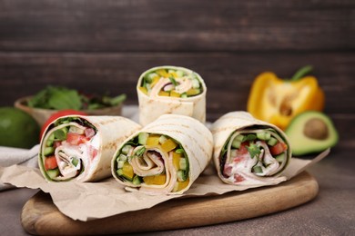 Photo of Delicious sandwich wraps with fresh vegetables on grey table