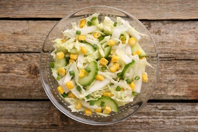 Photo of Tasty salad with Chinese cabbage, corn and cucumber in bowl on wooden table, top view