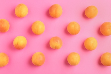 Delicious ripe sweet apricots on pink background, flat lay