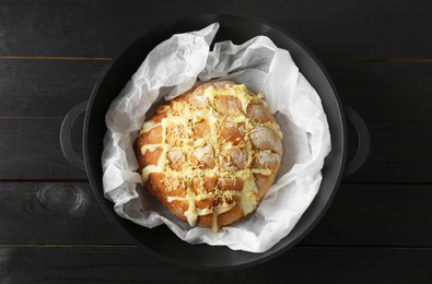Photo of Freshly baked bread with tofu cheese and lemon zest on black wooden table, top view