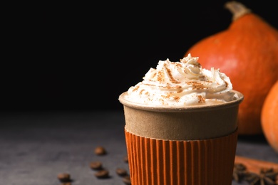 Photo of Paper cup of tasty pumpkin spice latte on gray table, closeup with space for text
