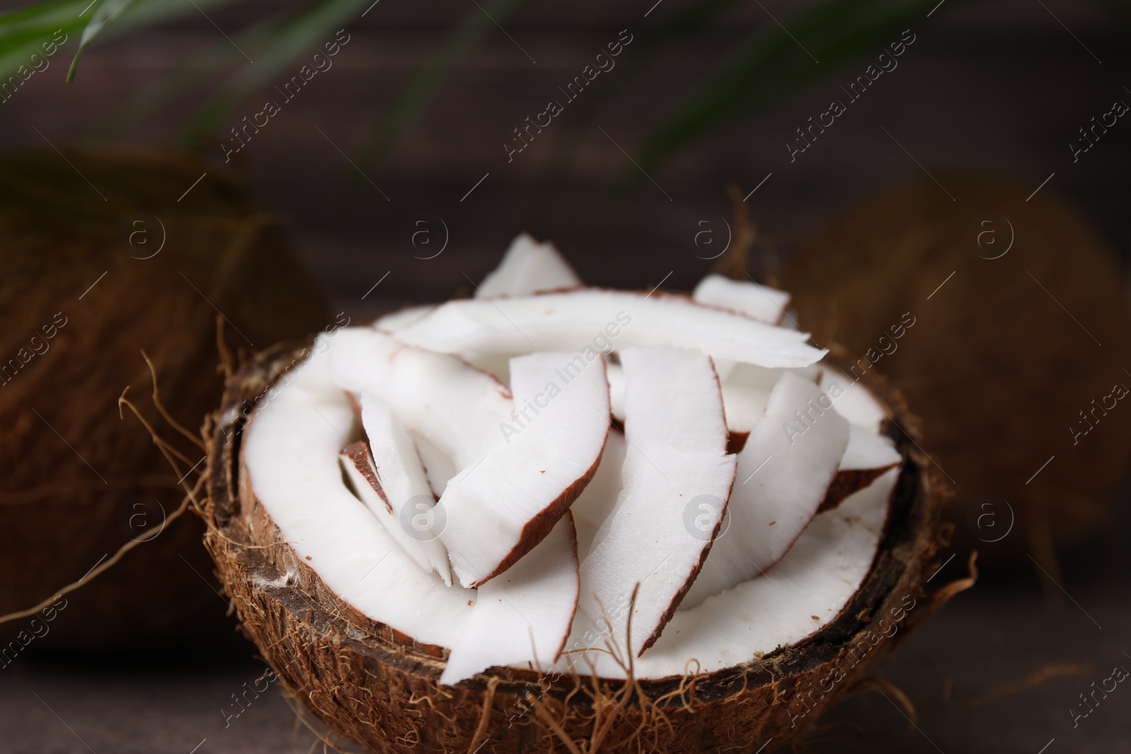 Photo of Coconut pieces in nut shell on table, closeup