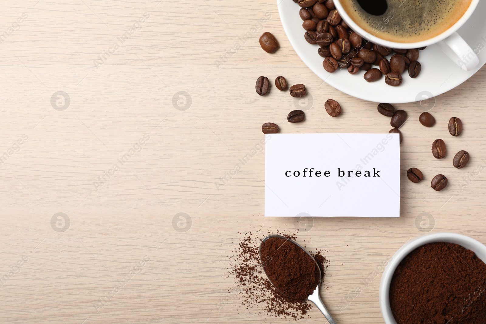 Photo of Cup hot of drink, beans, powder and card on wooden table, flat lay with space for text. Coffee break