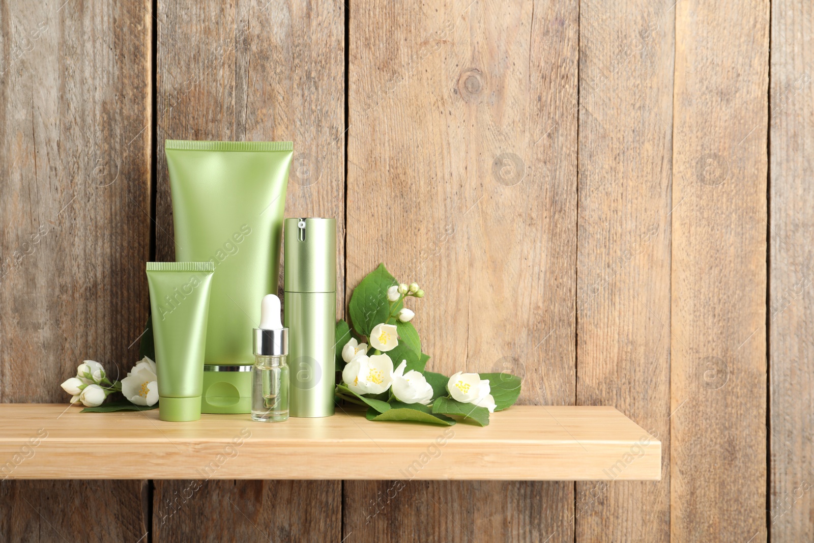 Photo of Set of cosmetic products and flowers on shelf near wooden wall, space for text