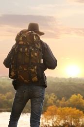 Photo of Traveler with backpack enjoying beautiful view near mountain river. Autumn vacation