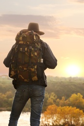 Traveler with backpack enjoying beautiful view near mountain river. Autumn vacation