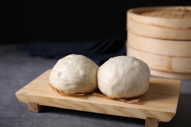 Photo of Delicious Chinese steamed buns on grey textured table, closeup