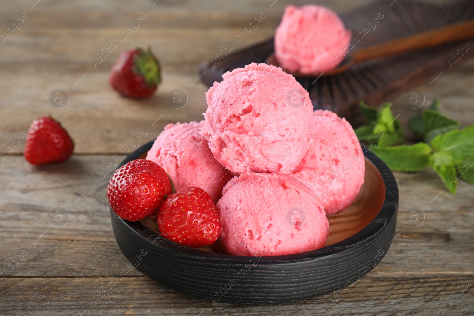 Photo of Plate with delicious strawberry ice cream on wooden table, closeup