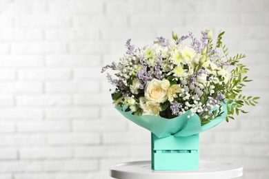 Photo of Beautiful bouquet of flowers in decorative crate on table against light background. Space for text