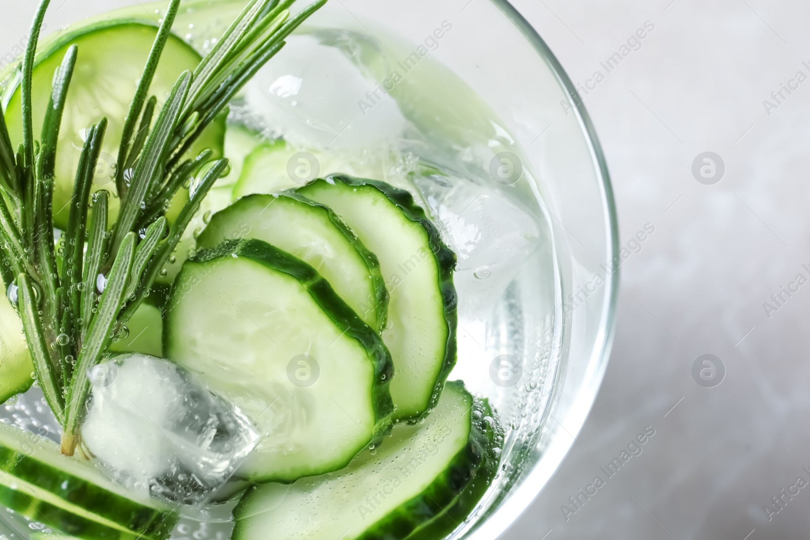 Photo of Glass of fresh cucumber water on light background, top view