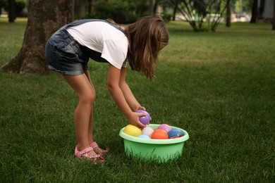 Photo of Little girl with basin of water bombs in park