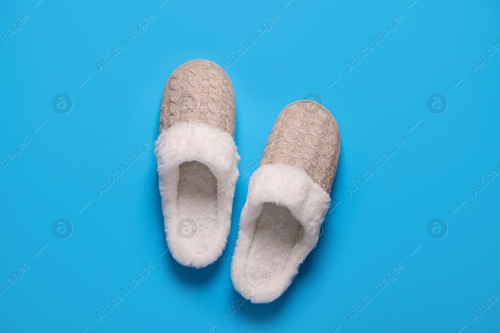 Photo of Pair of beautiful soft slippers on light blue background, top view