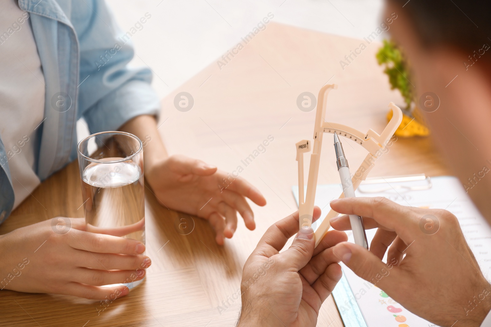 Photo of Nutritionist consulting patient at table in clinic, closeup