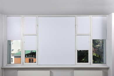 Large window with white roller blinds indoors