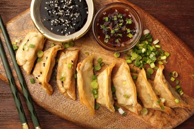 Photo of Delicious gyoza (asian dumplings) served on wooden table, top view