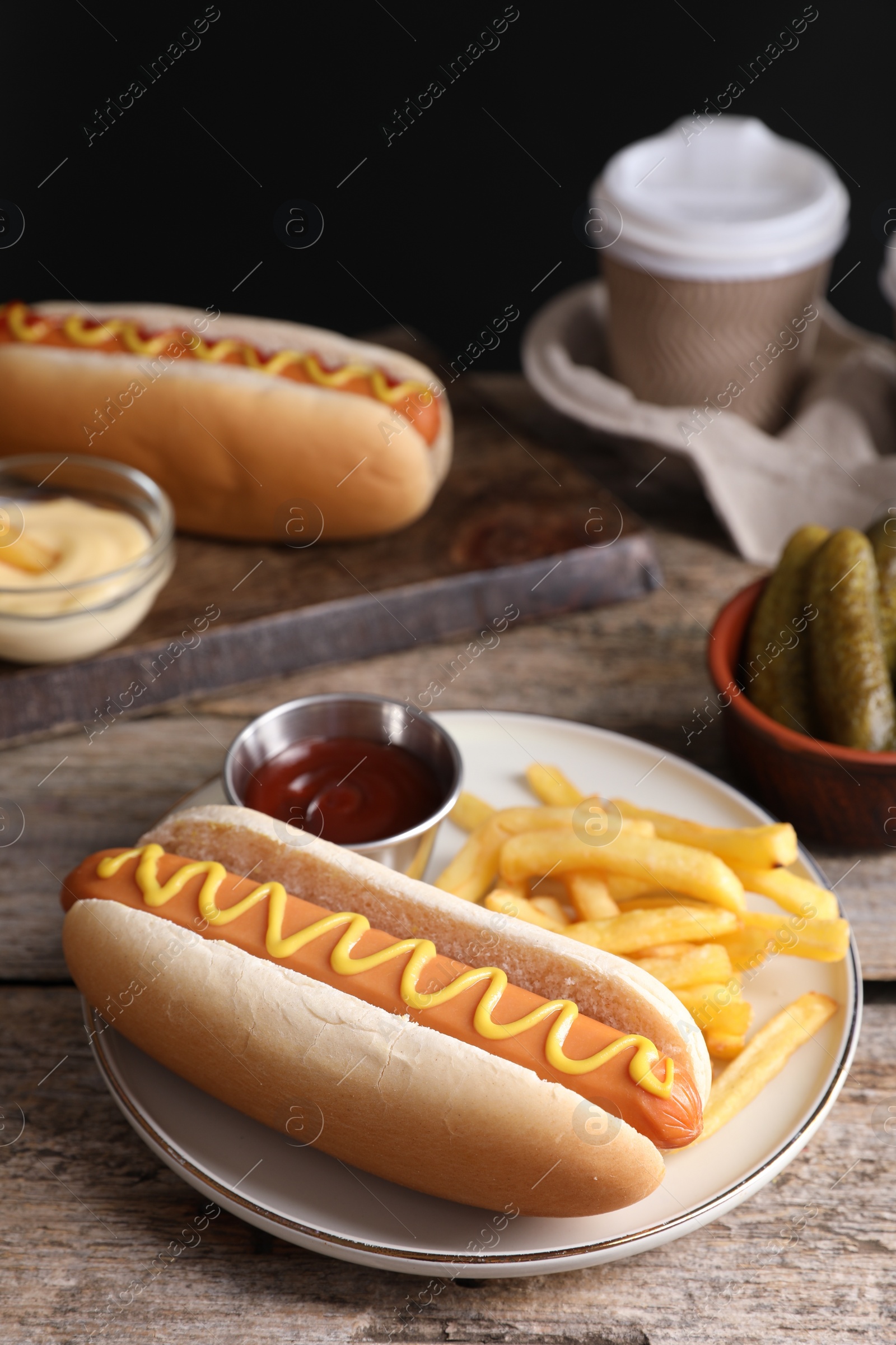 Photo of Delicious hot dog with ketchup, mustard and French fries on wooden table, closeup