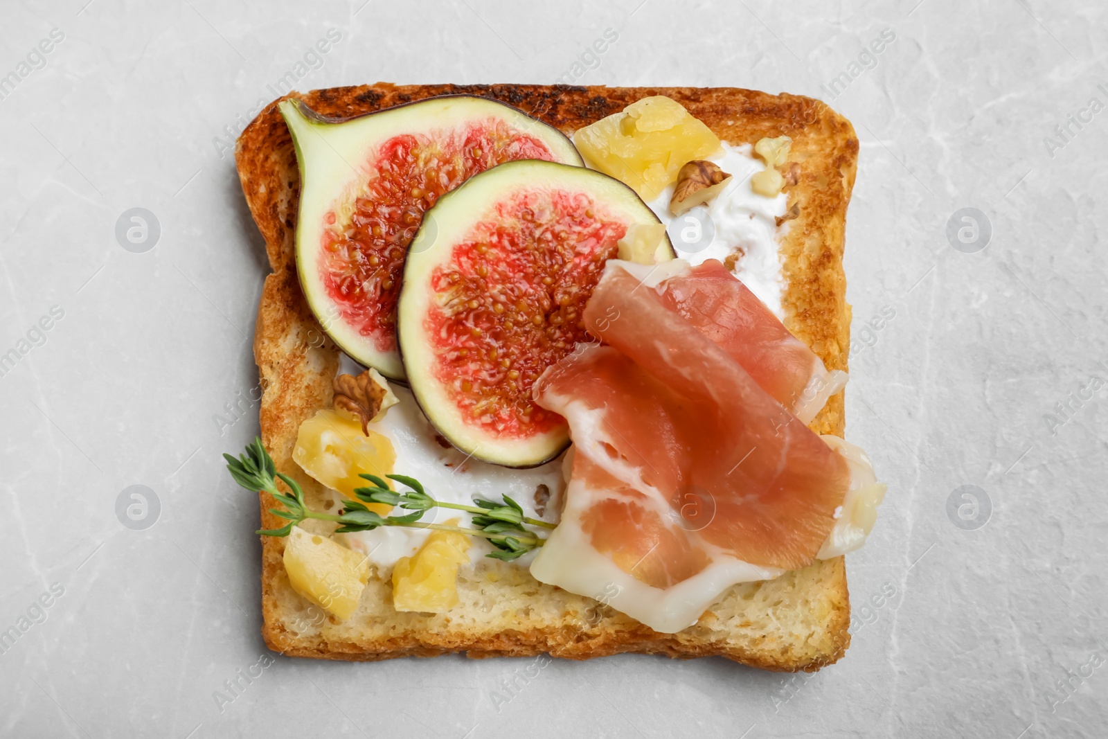 Photo of Delicious sandwich with figs, proscuitto and cheese on light table, top view