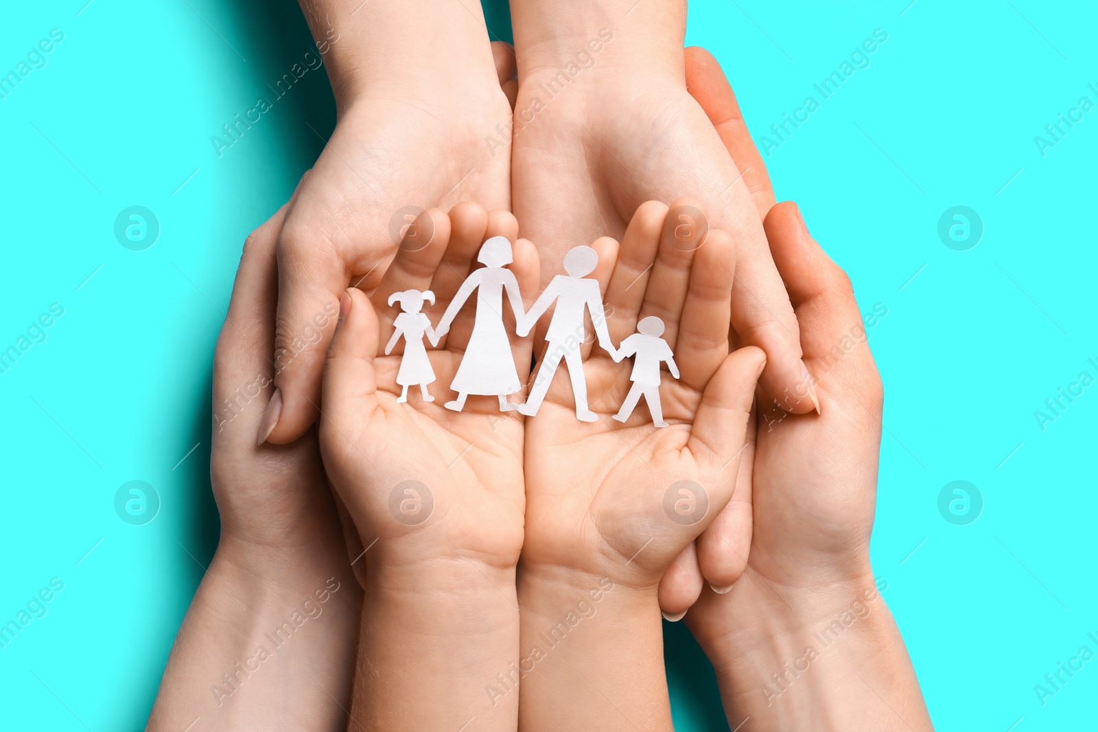 Photo of Parents and child holding paper cutout of family on light blue background, top view