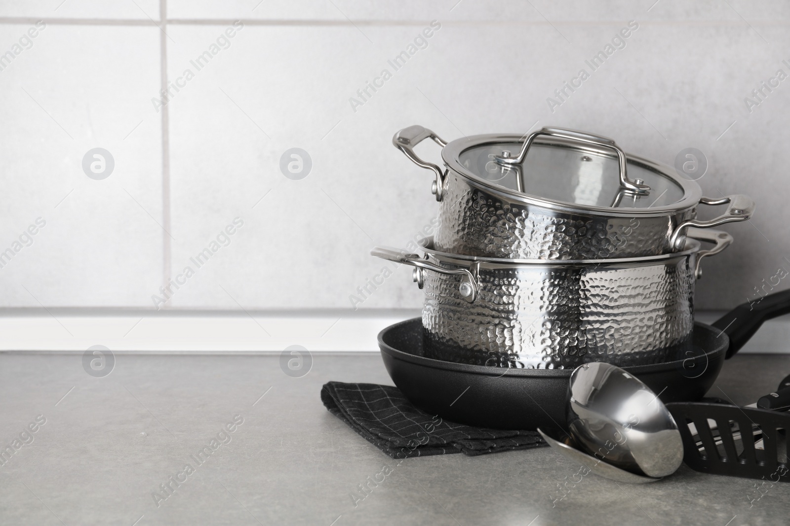 Photo of Set of different cooking utensils on grey countertop in kitchen. Space for text