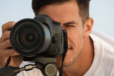 Photographer taking picture with professional camera, closeup