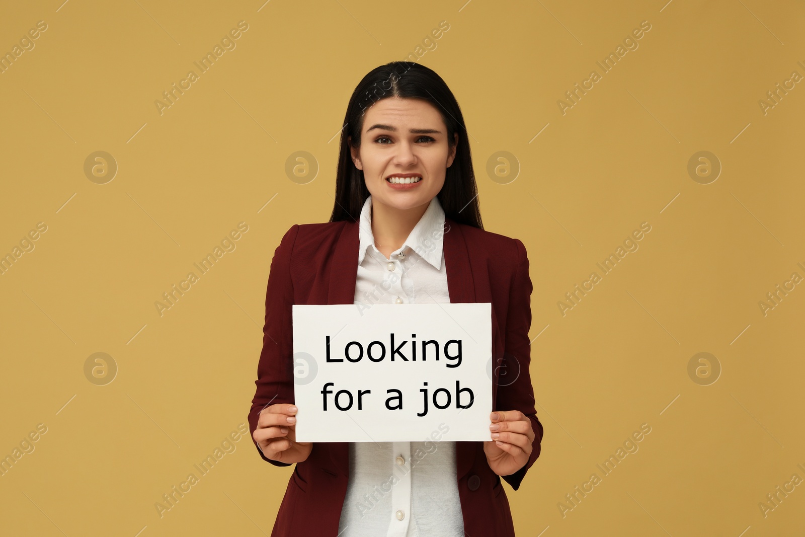 Photo of Unemployment problem. Unhappy woman holding sign with phrase Looking For A Job on pale orange background