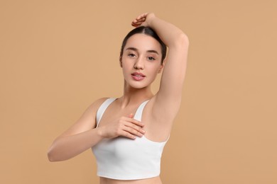 Beautiful woman showing armpit with smooth clean skin on beige background