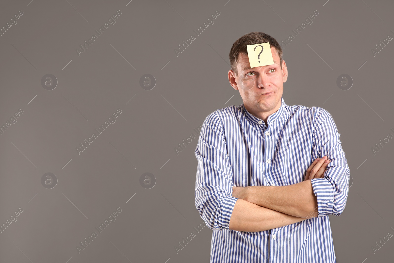 Photo of Emotional man with question mark on grey background, space for text