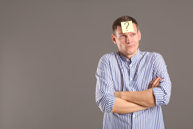 Photo of Emotional man with question mark on grey background, space for text