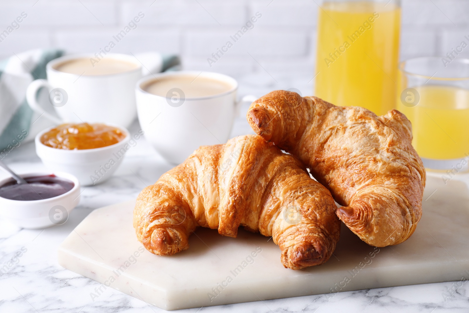 Photo of Tasty breakfast. Fresh croissants and jam on white marble table