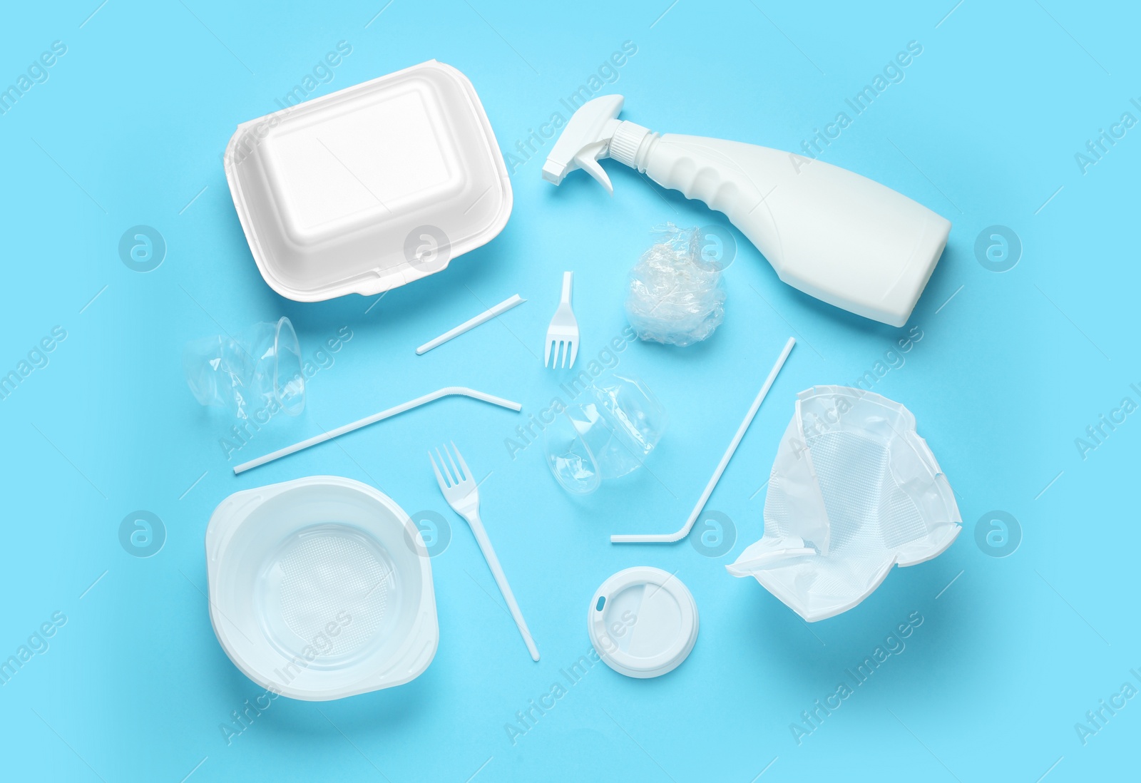 Photo of Different plastic items on light blue background, flat lay
