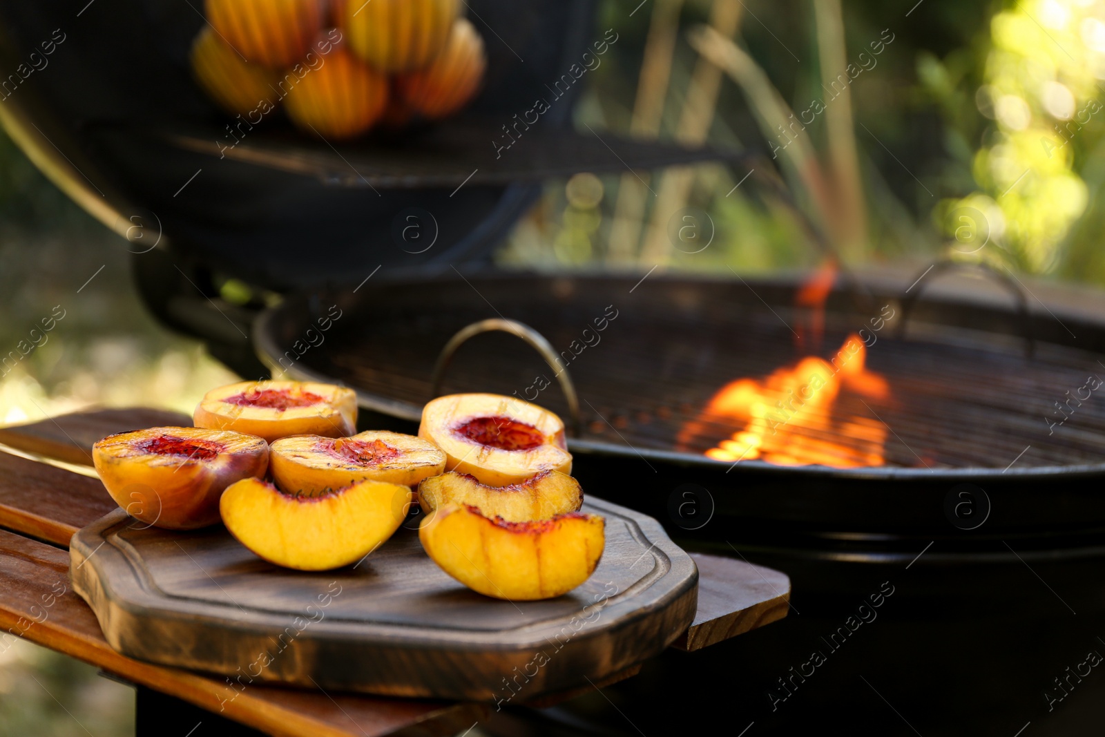 Photo of Delicious grilled peaches on wooden table outdoors