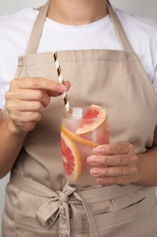 Photo of Woman holding glass of grapefruit refreshing drink with straw, closeup