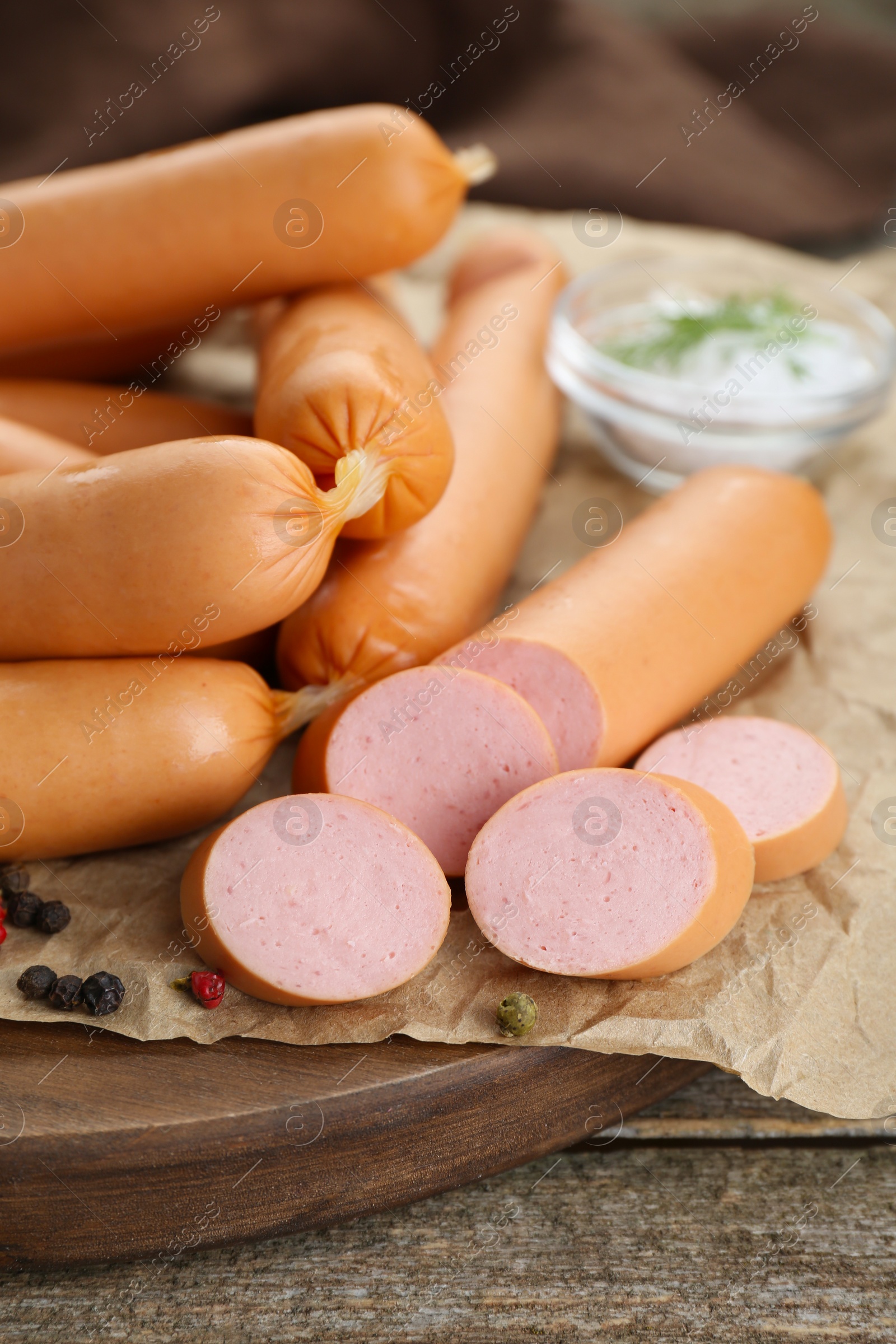 Photo of Tasty sausages and peppercorns on wooden table, closeup. Meat product