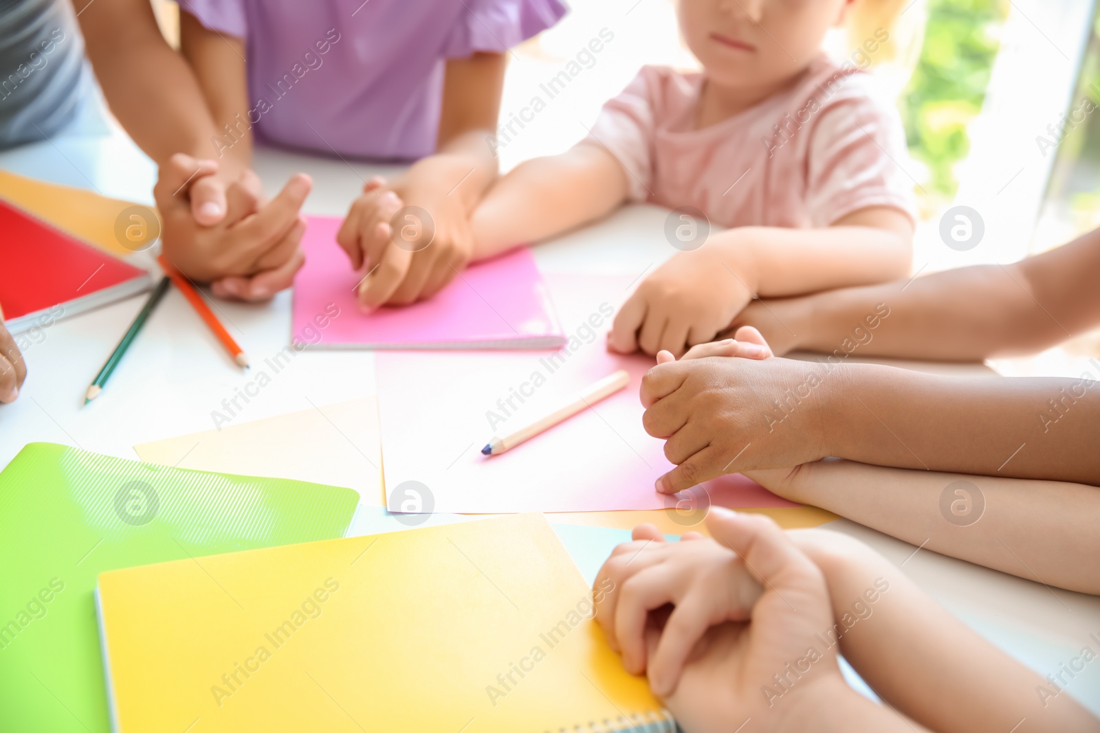 Photo of Little children holding hands at table, closeup. Unity concept