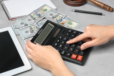 Photo of Woman using calculator at table, closeup. Tax law concept