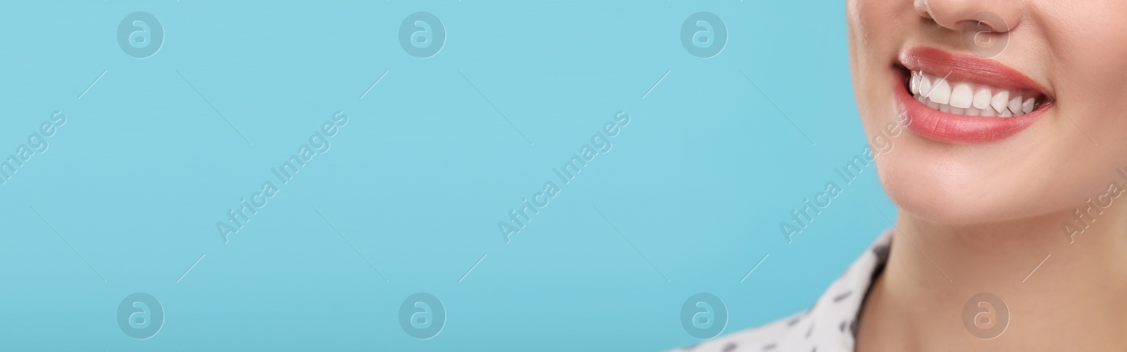 Image of Woman with clean teeth smiling on light blue background, closeup. Banner design with space for text