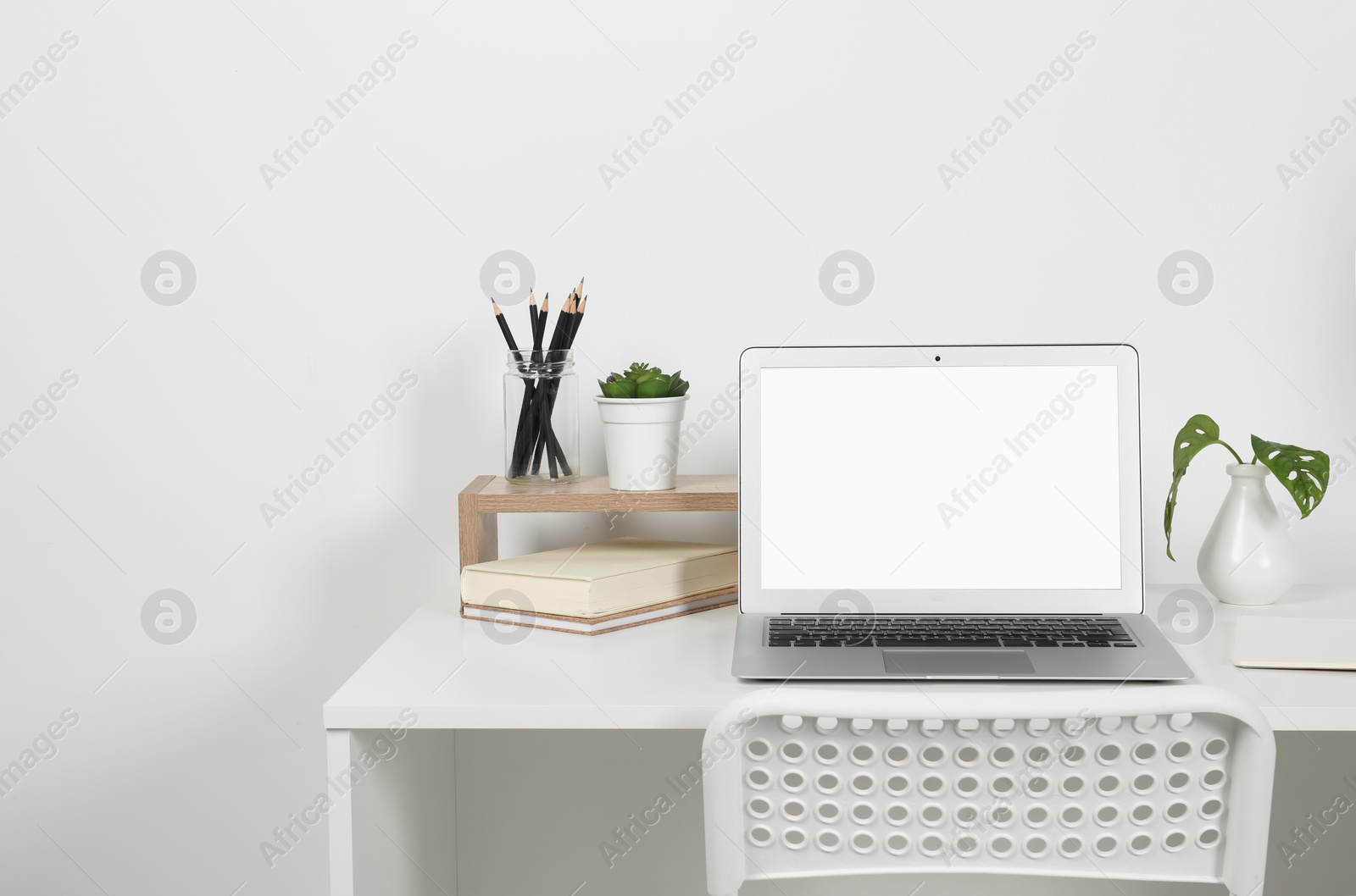 Photo of Cozy workspace with laptop, lamp and stationery on wooden desk at home